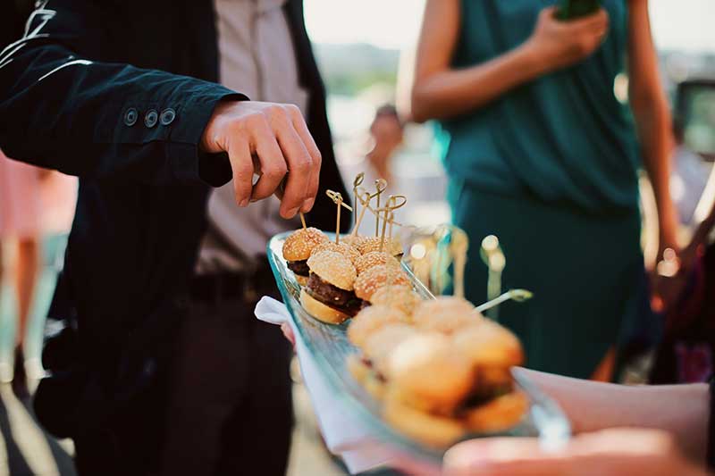 off-site catering menu quincy ma - A waiter with a tray of snacks at a banquet or reception. Catering buffet at party